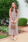 Woman in a checkered dress holding a small bag outdoors.