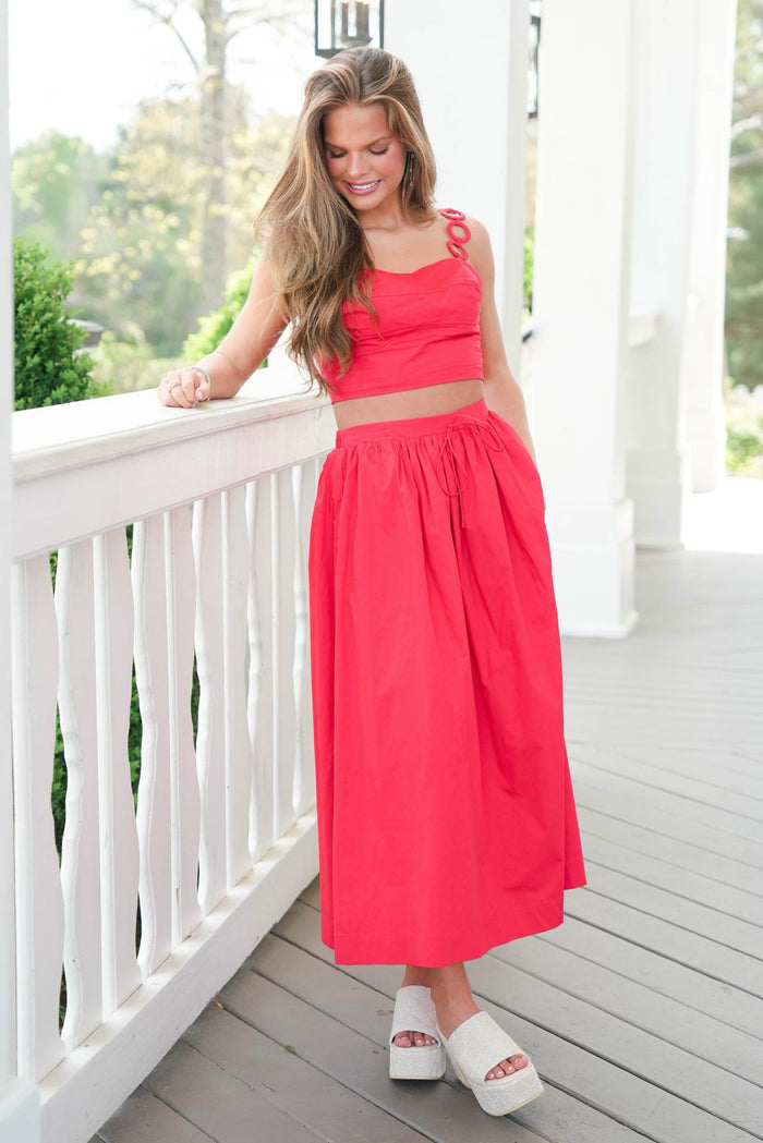 Woman in a red outfit standing on a white porch