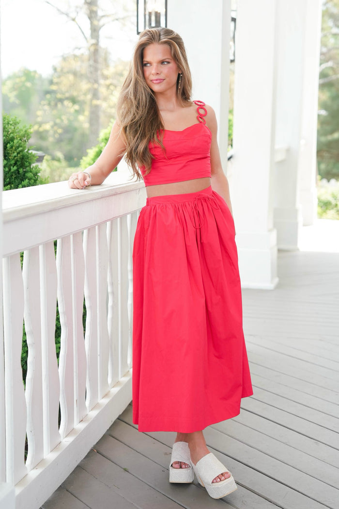 Woman in a red outfit standing on a white porch