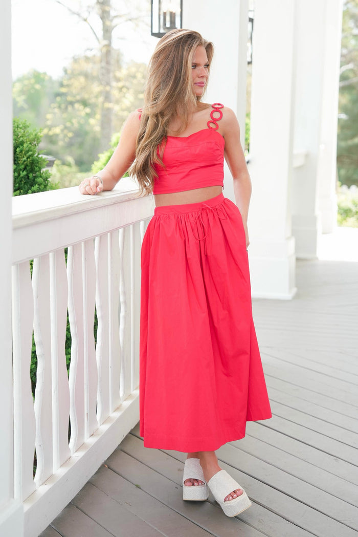 Woman in a red dress standing on a white porch