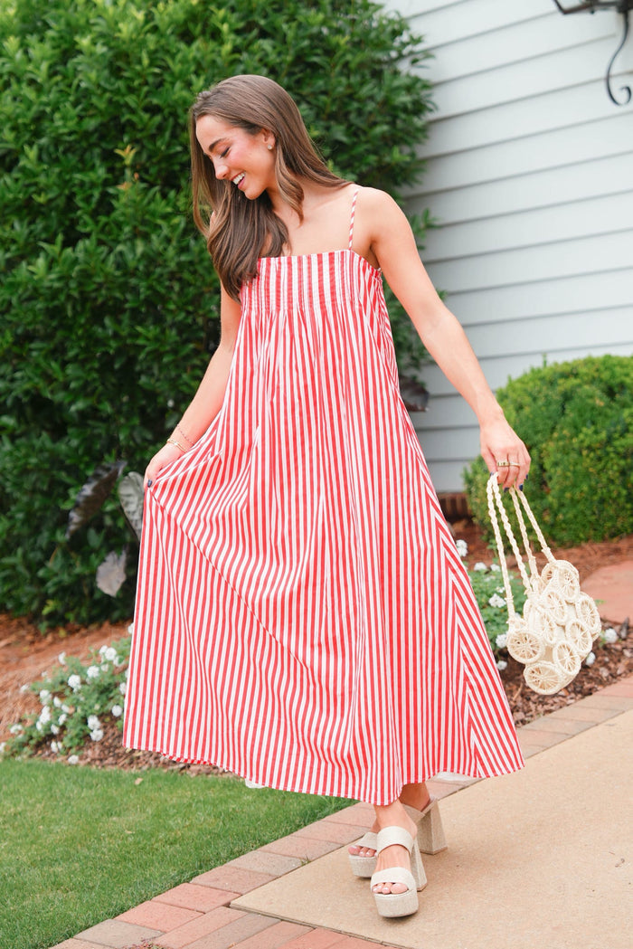 Woman in a red and white striped dress standing outdoors.