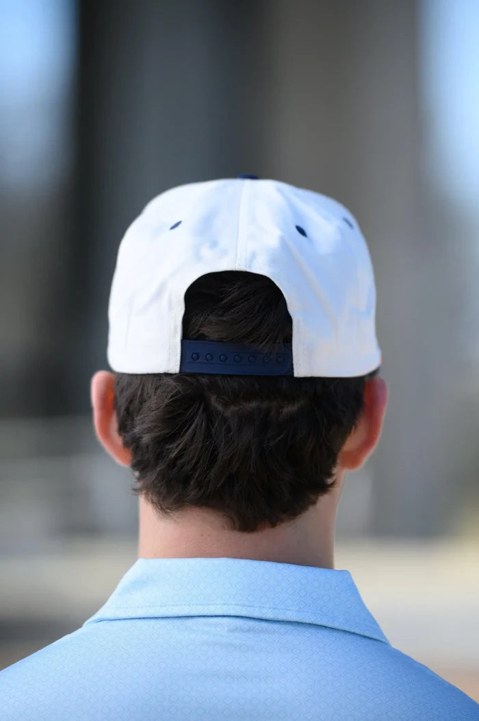 Person wearing a white cap with a blue logo, facing away from the camera.