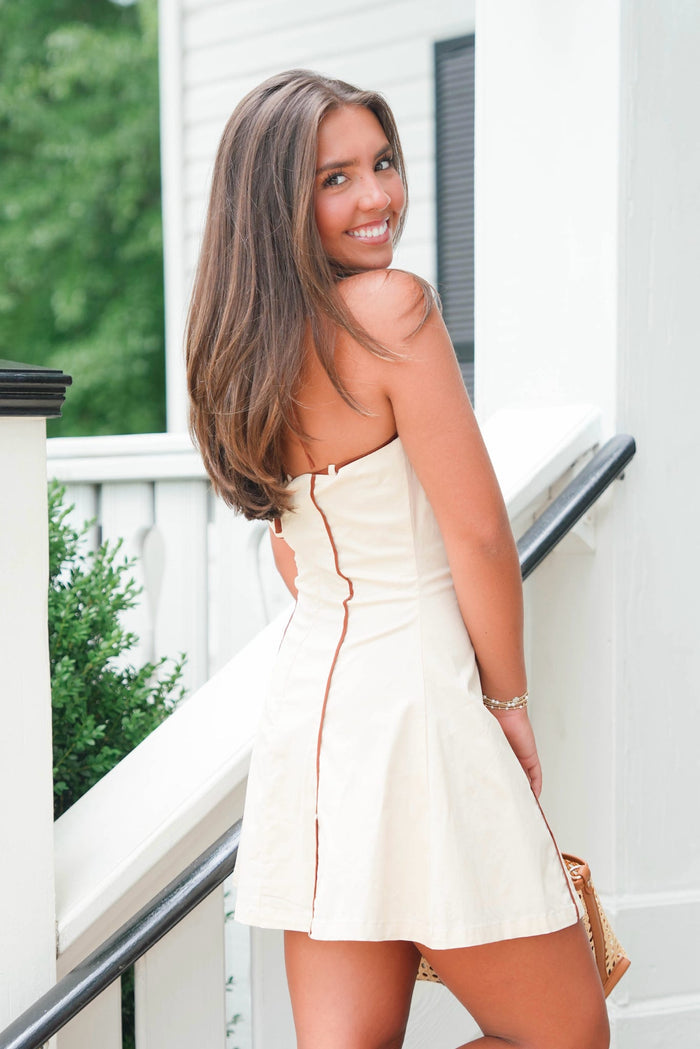 Woman in a white strapless dress standing on a staircase with greenery in the background