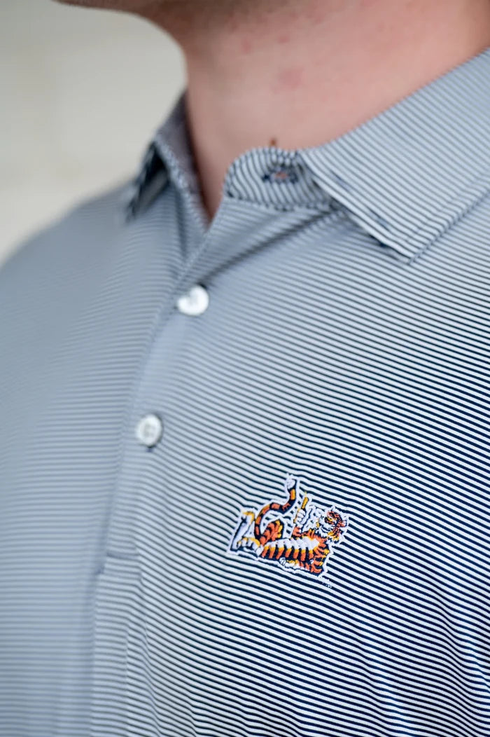 Close-up of a person wearing a blue and white striped polo shirt with a small embroidered tiger patch on the chest.