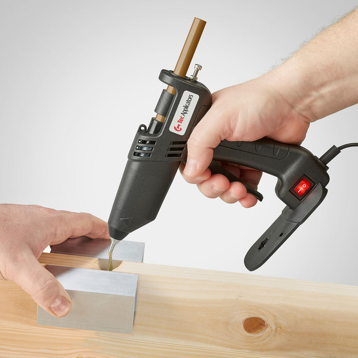 During a woodworking repair, adhesive is dispensed into a wood gap with a handheld Tec 305 hot melt gun by Power Adhesives