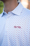 Close-up of a person wearing a white short-sleeve collared button-up shirt with a red micro-dot pattern and a red embroidered 'Roll Tide' logo on the chest.