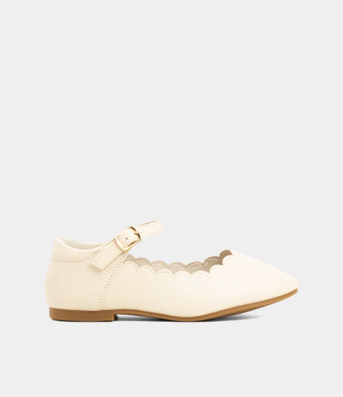 An off-white pointed-toe flat shoe with a scalloped edge and a small strap detail with a buckle, shown from a side profile on a light gray background.