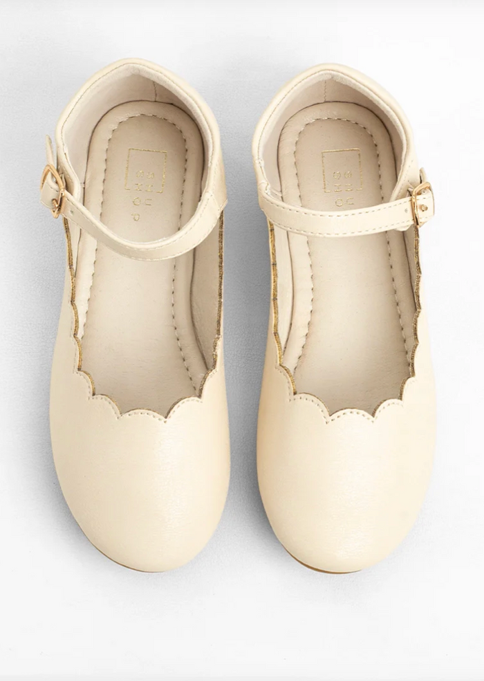 A pair of cream-colored faux leather Mary Jane shoes with scalloped edges and ankle straps, shown from a top-down view on a white background.