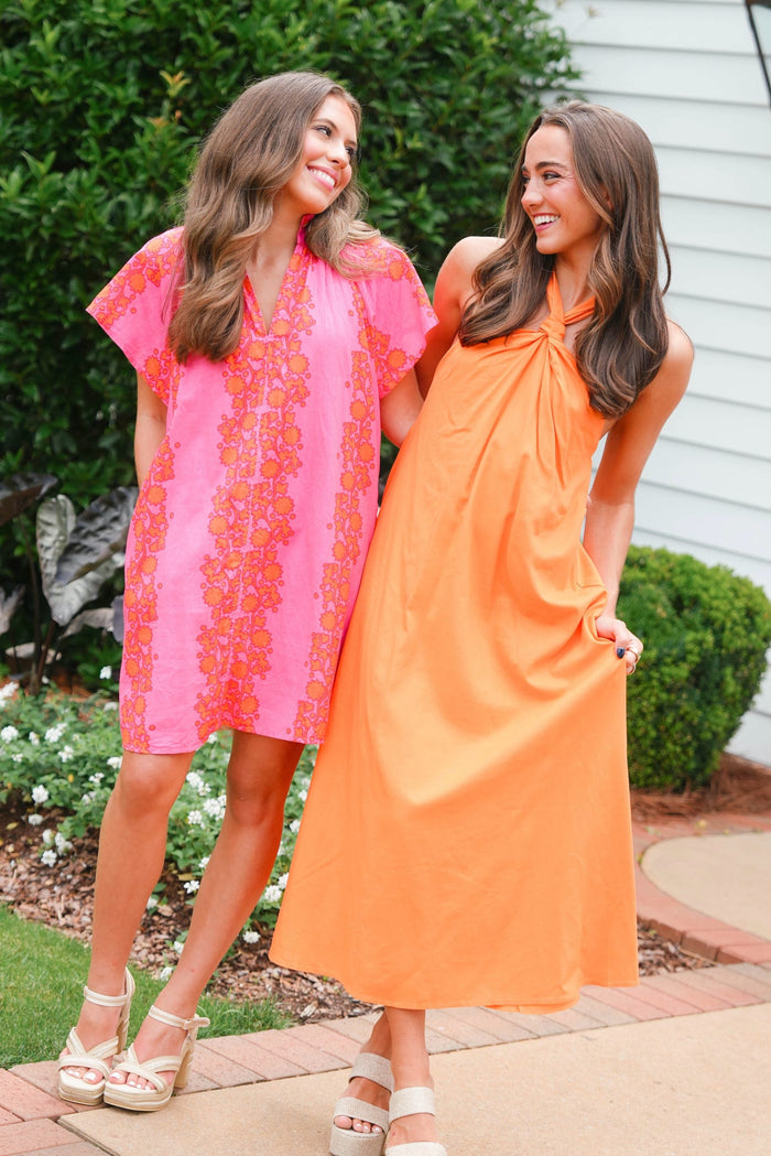 Two women wearing colorful dresses standing outdoors.