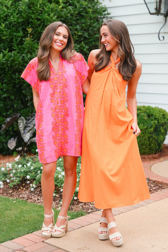 Two women wearing colorful dresses standing outdoors.
