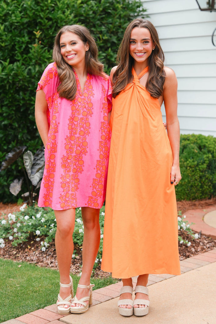 Two women wearing colorful dresses standing outdoors.