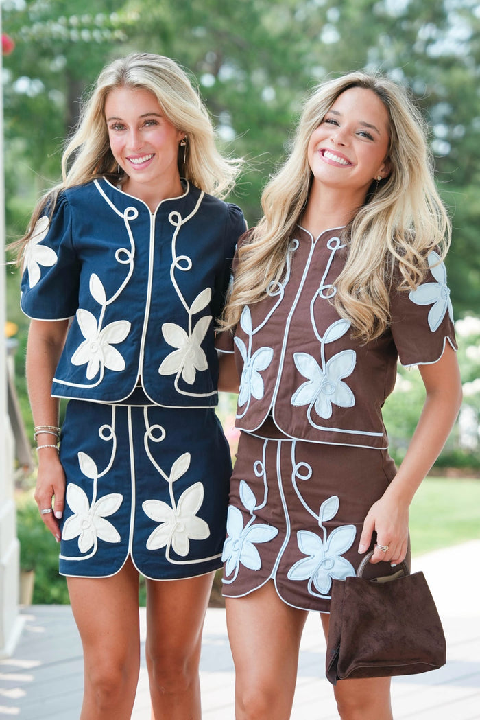 Two women wearing matching floral outfits standing outdoors.