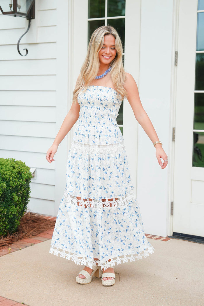Woman in a floral dress standing outside a house