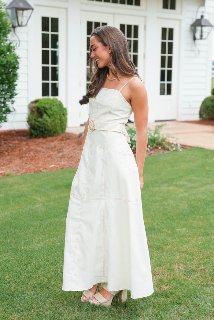 Woman in a white dress standing on grass in front of a house