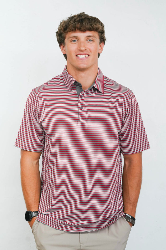 A man wearing a short-sleeve polo shirt with thin horizontal red and navy stripes on a white background.