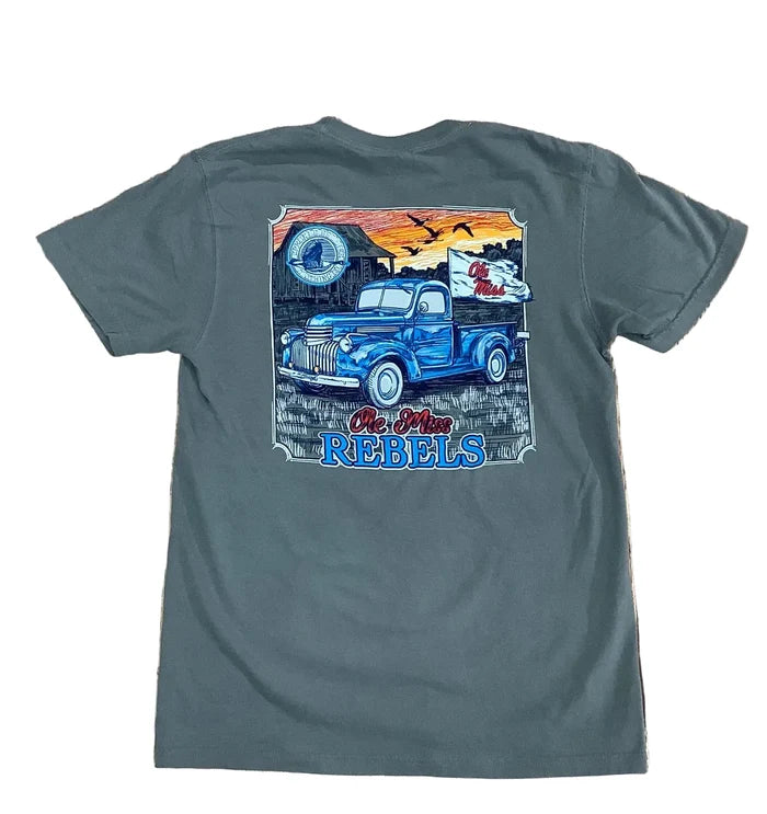 A dark gray t-shirt laid flat on a rustic wooden background, featuring a large graphic print on the back with a blue vintage pickup truck, a cowboy, a horseshoe, and the text 'The Old Rebels'.