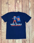 A navy blue short-sleeve t-shirt featuring a graphic of the Auburn University War Eagle mascot holding a blue flag with an orange 'AU' logo, with 'WAR EAGLE' and 'AUBURN UNIVERSITY' printed in white and orange below. The shirt is laid flat on a rustic wooden plank background.