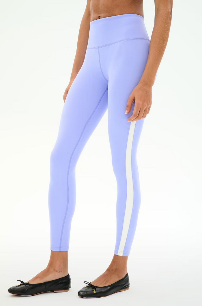 A model wearing light purple high-waisted leggings with a white side stripe, paired with black ballet flats, shown against a plain white background.