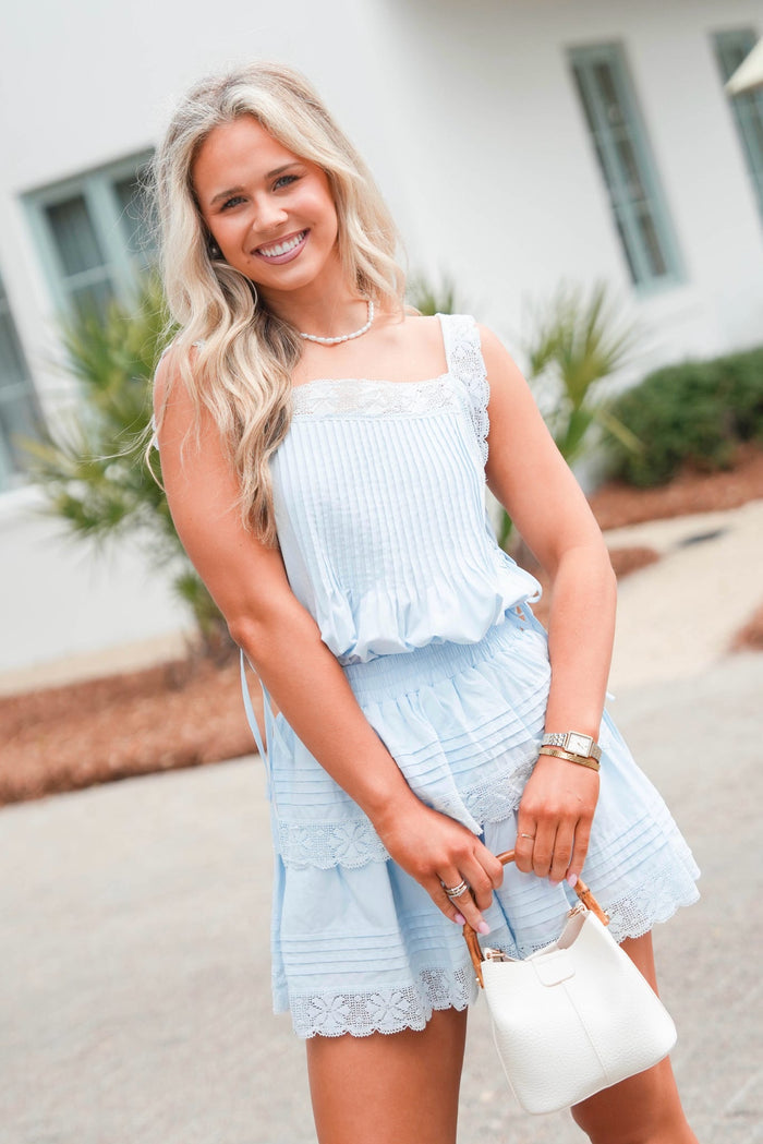 Woman wearing a light blue dress with ruffled details outdoors.