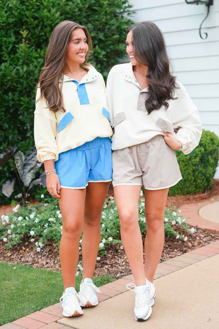 Two women standing outdoors wearing matching outfits with blue and beige tones.