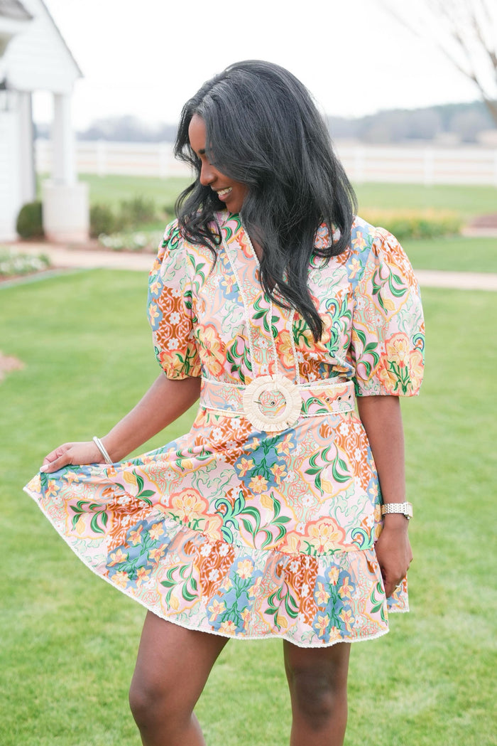 Woman in a floral dress standing on grass with a blurred background