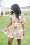 Woman in a floral dress standing on grass with a blurred background