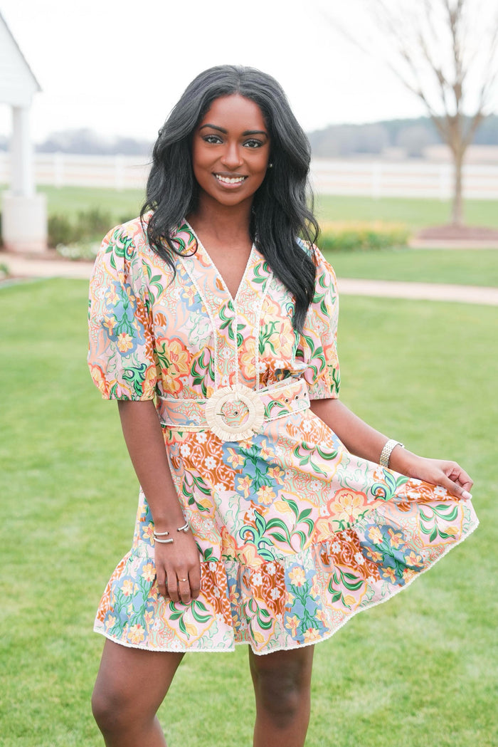 Woman wearing a floral dress standing on grass with a blurred background