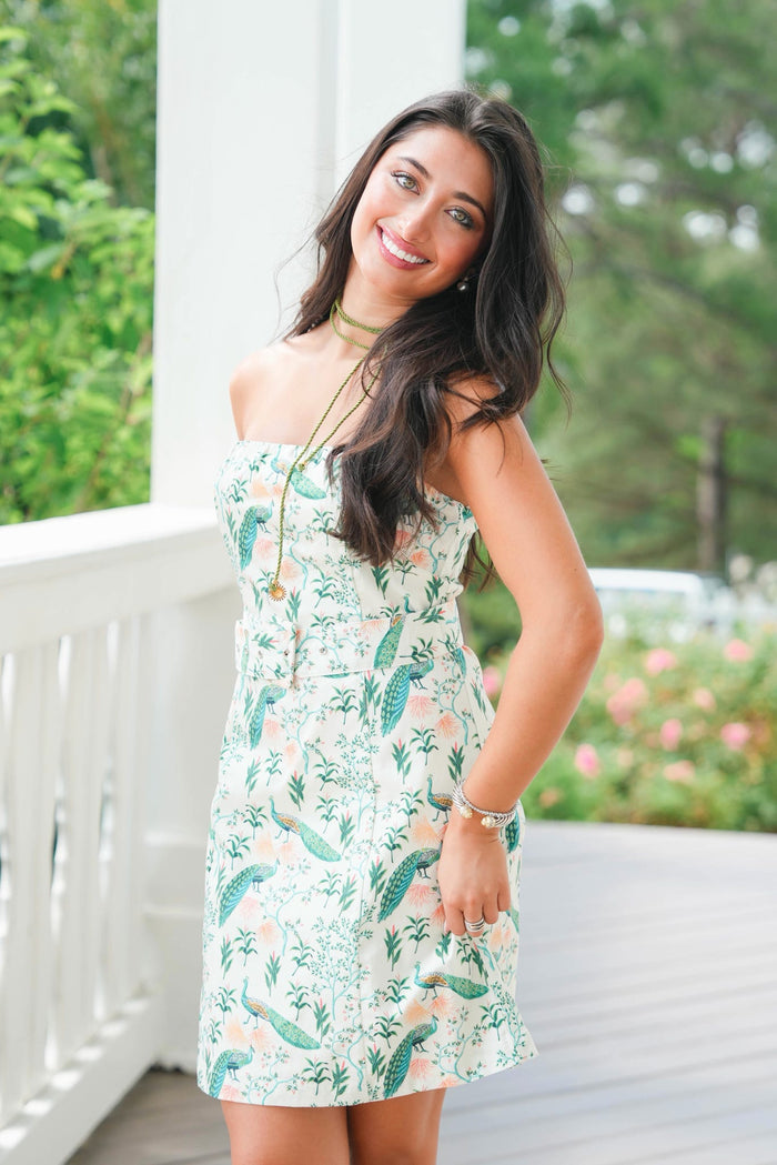 Woman wearing a floral dress on a porch with greenery in the background