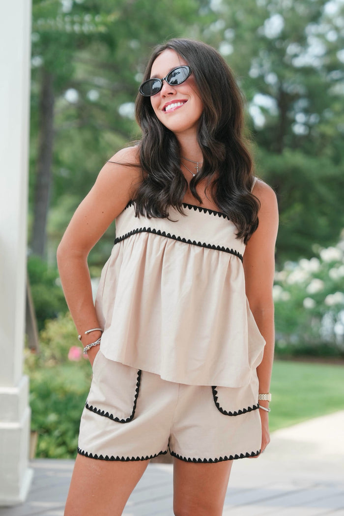 Woman wearing a beige romper with black trim outdoors