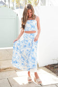 Woman wearing a blue floral two-piece outfit standing outdoors.