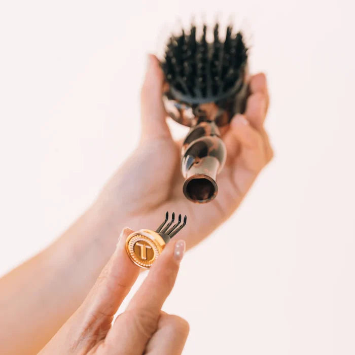 Hand holding a hairbrush with a close-up of bristle tips on a light background