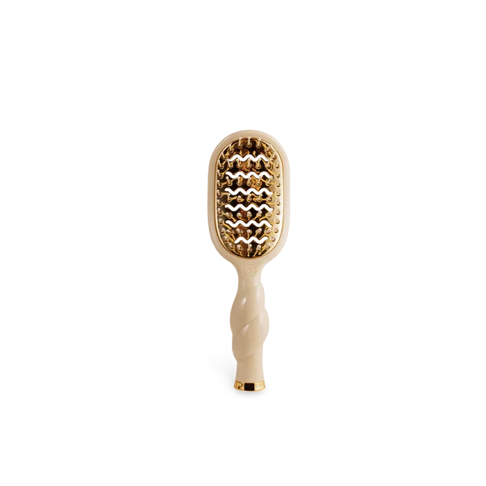 Hairbrush with gold bristle head and beige handle on a white background
