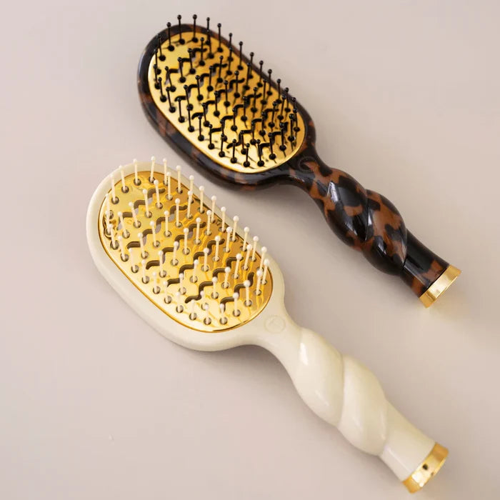 Two hairbrushes with tortoiseshell and white handles on a beige background