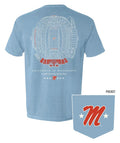 A light blue t-shirt shown from the back, featuring a detailed white and red stadium floor plan graphic with 'UNIVERSITY OF MISSISSIPPI' and 'Violetta Homecoming Stadium' printed below. A small inset in the bottom right corner shows a matching pocket graphic with a red 'M' and white stars on the light blue fabric.