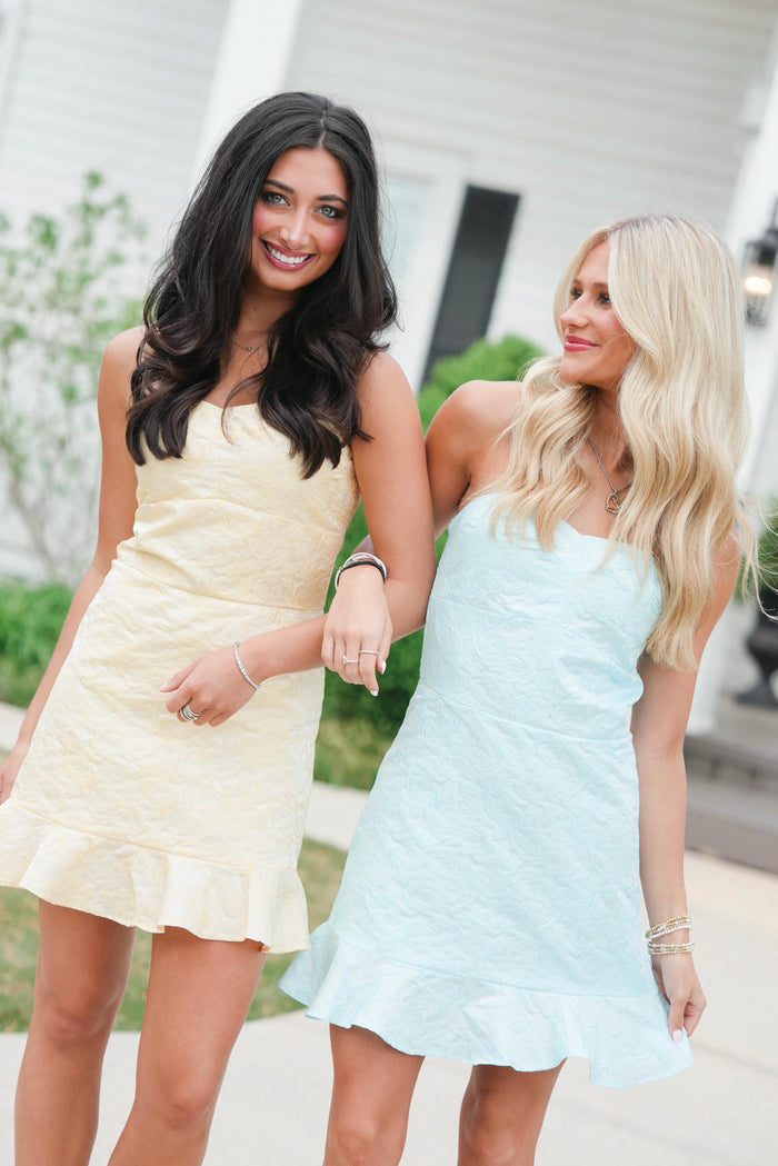 Two women in light-colored dresses standing outdoors.