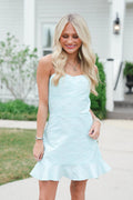 Woman wearing a light blue dress standing outdoors.
