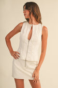 Woman wearing a white sleeveless top and skirt set against a beige background