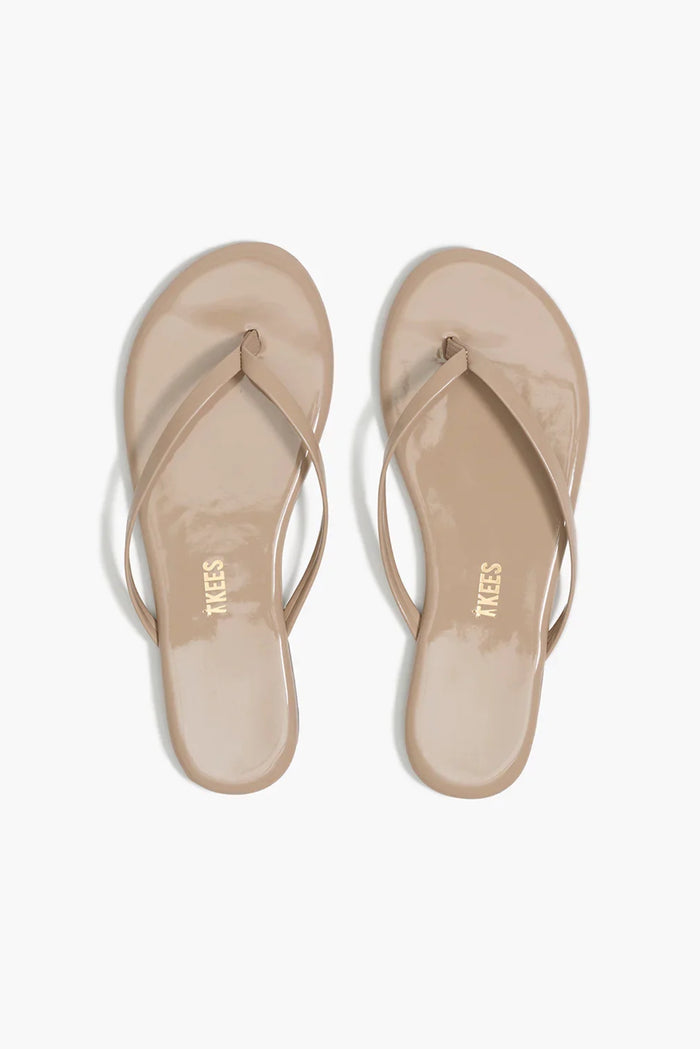 Pair of beige sandals with 'Tkees' branding on a white background