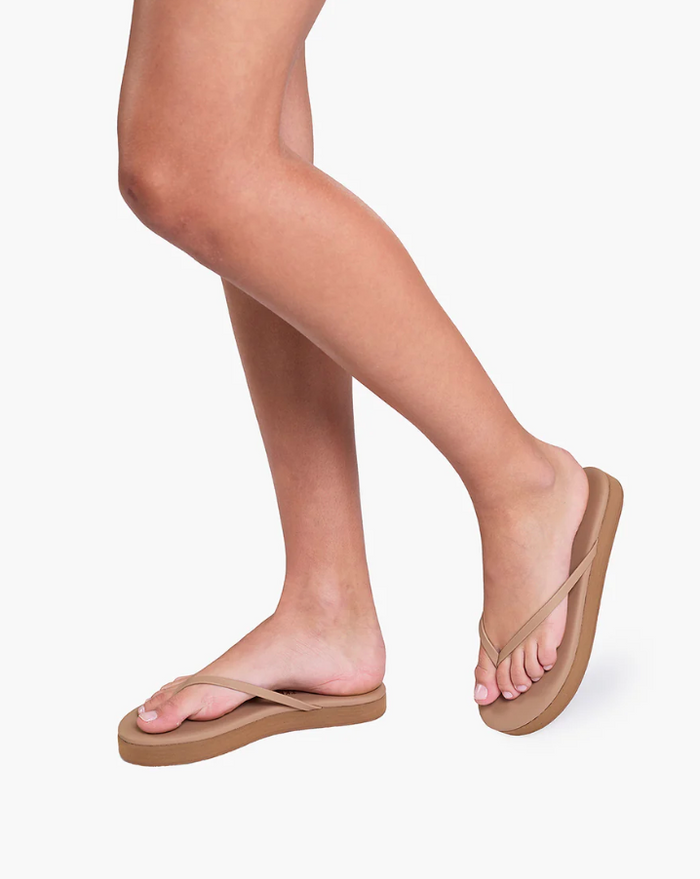Tan flip-flops worn by a person on a white background