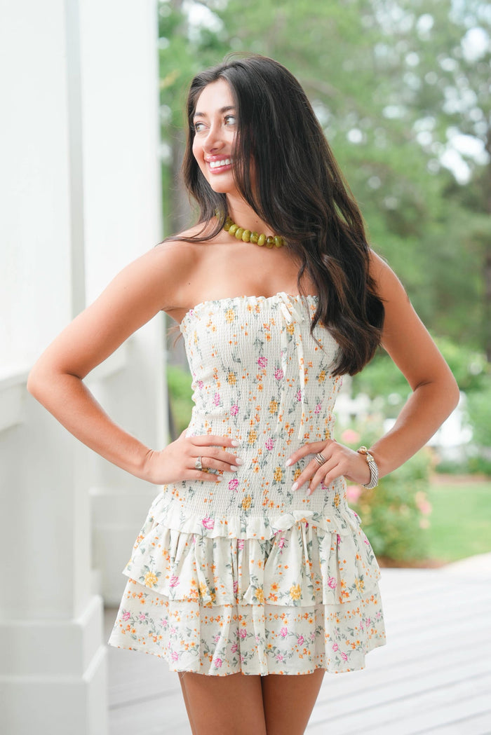 Woman wearing a floral dress standing outdoors with greenery in the background