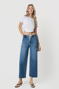 Woman wearing blue jeans and a white crop top on a white background