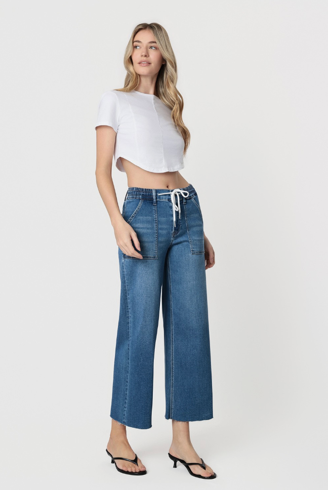 Woman wearing a white crop top and blue jeans on a white background
