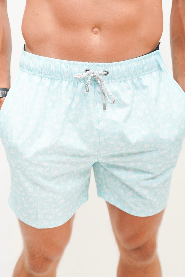 Light blue swim shorts with a subtle pattern worn by a person on a plain background