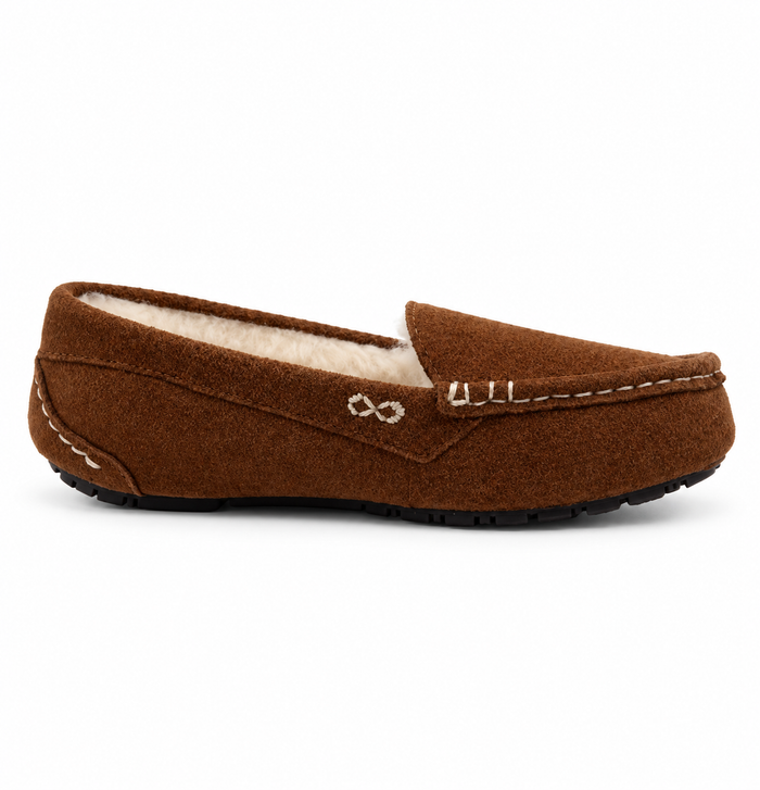 A single brown suede slip-on loafer with a cream sherpa lining, featuring contrast stitching, a decorative metal emblem, and a black outsole, shown against a plain white background.