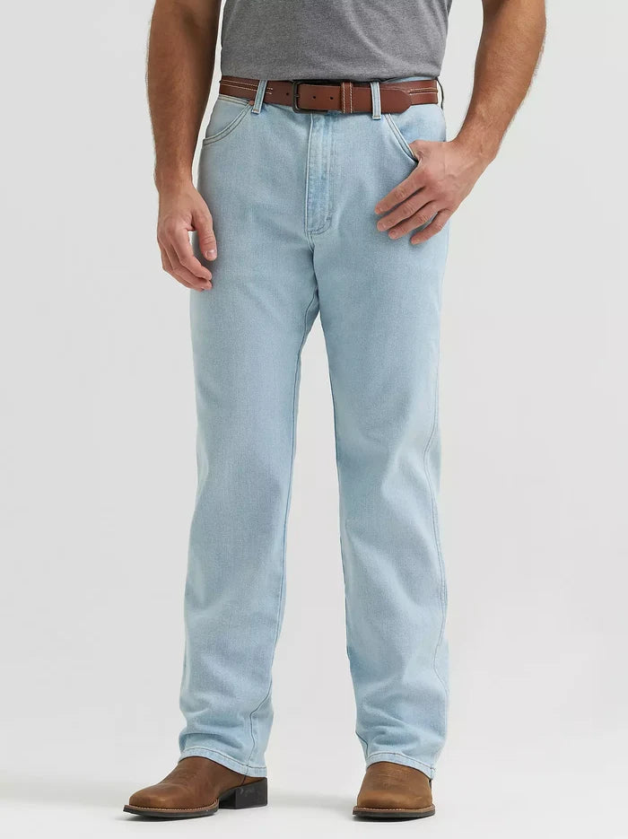 A person wearing light-wash blue jeans with a brown belt and brown boots, shown from the waist down against a plain light gray studio background.